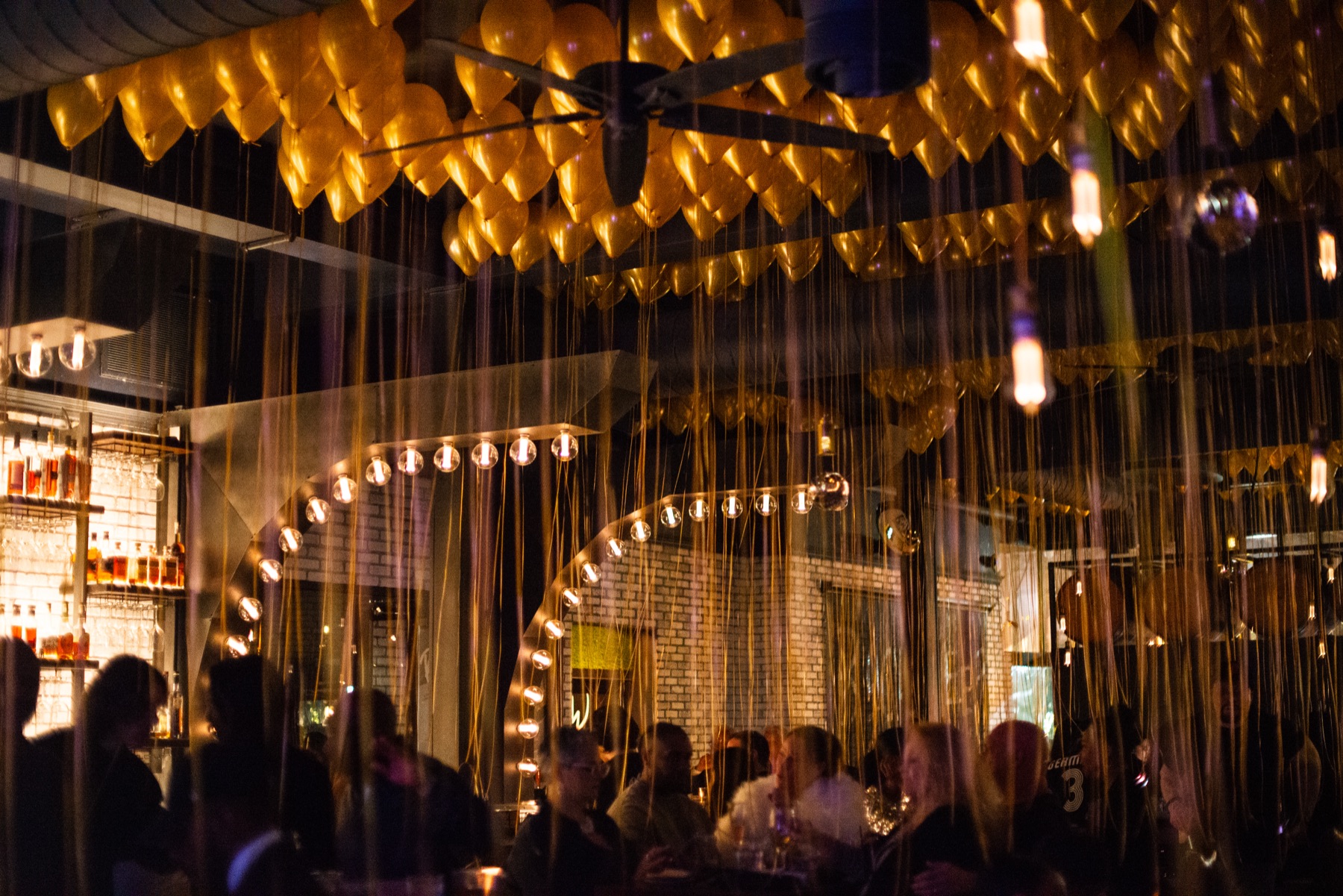Guests celebrating beneath gold balloons at BlackSheep